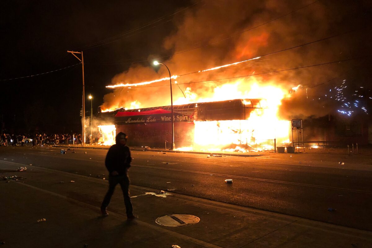 Flames rise from a liquor store near the Third Police Precinct on May 28, 2020 in Minneapolis, Minnesota, during a protest over the death of George Floyd, an unarmed black man, who died after a police officer kneeled on his neck for several minutes. - A police precinct in Minnesota went up in flames late on May 28 in a third day of demonstrations as the so-called Twin Cities of Minneapolis and St. Paul seethed over the shocking police killing of a handcuffed black man. The precinct, which police had abandoned, burned after a group of protesters pushed through barriers around the building, breaking windows and chanting slogans. A much larger crowd demonstrated as the building went up in flames.