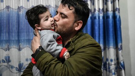 Hamid Safi, a taxi driver who found Sohail Ahmadi on the ground at Kabul airport and tracked down the family, kisses Sohail, who was separated from his parents at the airport in the chaos of the US evacuation of Afghanistan in August 2021, at Sohail's grandfather's house in Kabul on January 9, 2022. (Photo by Mohd RASFAN / AFP) (Photo by MOHD RASFAN/AFP via Getty Images)