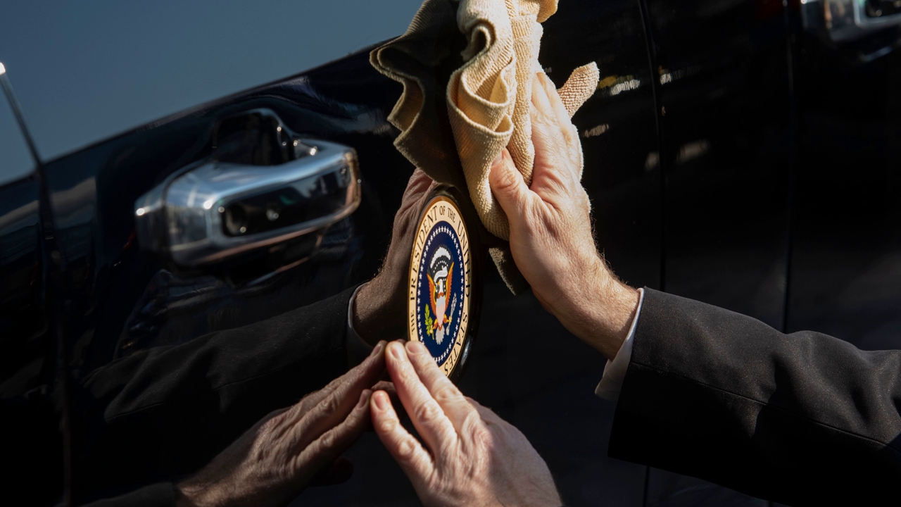 A Secret Service agent cleans around a Presidential Seal on the new car of US President Joe Biden, parked at the US Capitol in Washington, DC on January 20, 2021. 