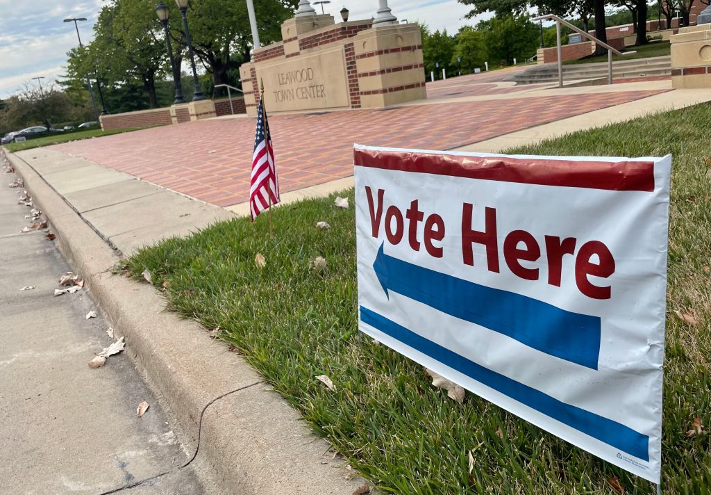 vote here sign and american flag in front of voting precinct