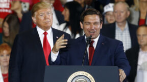 Donald Trump stands behind Ron DeSantis as he speaks at a rally
