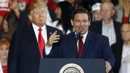 Donald Trump stands behind Ron DeSantis as he speaks at a rally