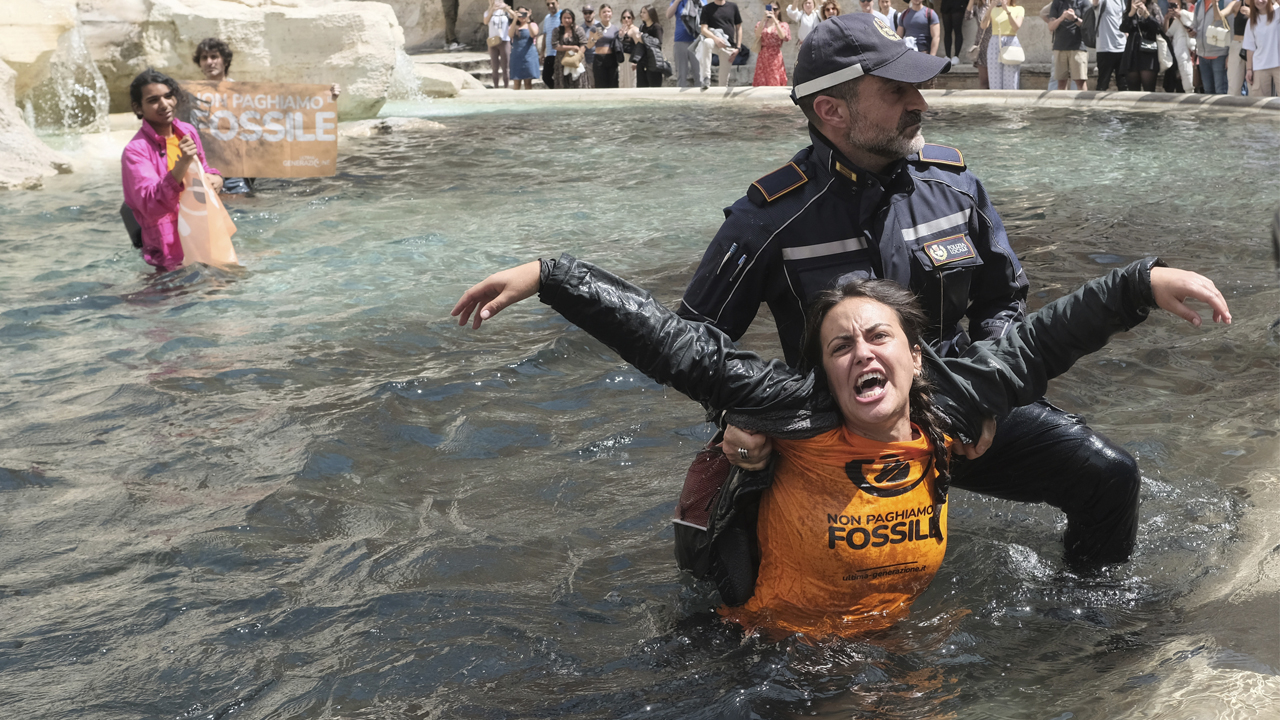 Last Generation environmentalists are being taken out after showing a banner against the use of fossil fuels in the Trevi Fountain in Rome, Sunday, May 21, 2023