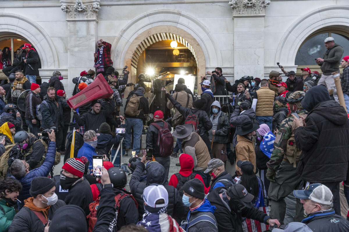 Rioters clash with police trying to enter Capitol building through the front doors in Washington, DC on January 6, 2021. Rioters broke windows and breached the Capitol building in an attempt to overthrow the results of the 2020 election. Police used buttons and tear gas grenades to eventually disperse the crowd. Rioters used metal bars and tear gas as well against the police.