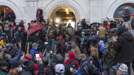 Rioters clash with police trying to enter Capitol building through the front doors in Washington, DC on January 6, 2021. Rioters broke windows and breached the Capitol building in an attempt to overthrow the results of the 2020 election. Police used buttons and tear gas grenades to eventually disperse the crowd. Rioters used metal bars and tear gas as well against the police.