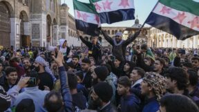 Syrians chant slogans and wave the new Syrian flag as they gather for Friday prayers at the Umayyad mosque in Damascus.