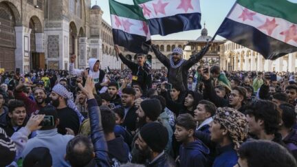 Syrians chant slogans and wave the new Syrian flag as they gather for Friday prayers at the Umayyad mosque in Damascus.