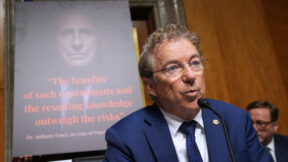 Rand Paul with image of anthony fauci on a screen behind him