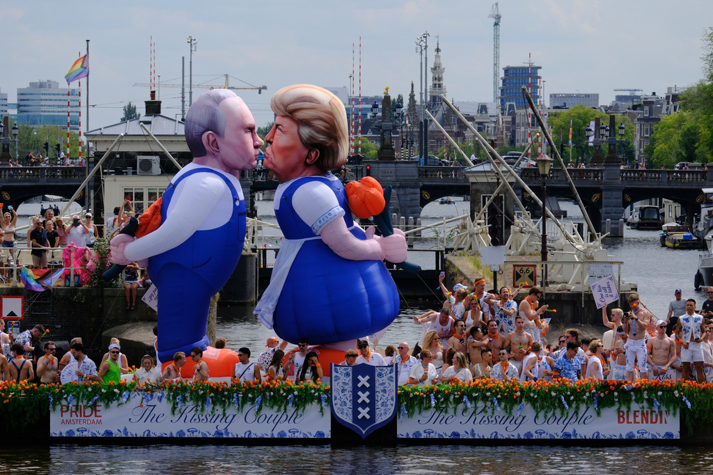 Two inflatable caricature balloons depicting U.S. President Donald Trump, center, and Russian President Vladimir Putin, left, as people line the Dutch capital's historic canals Saturday, Aug. 1, 2026, to watch the Amsterdam Pride Canal Parade. (AP Photo/Patrick Post)