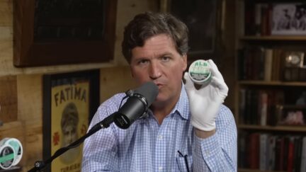 Tucker Carlson holds up one of his Alp patches
