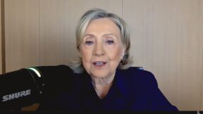 HIllary Clinton sitting at a mic for a podcast