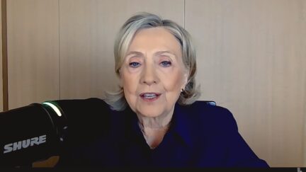 HIllary Clinton sitting at a mic for a podcast
